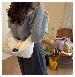 Detail of off-white nylon dumpling bag with pleated texture and black brand label