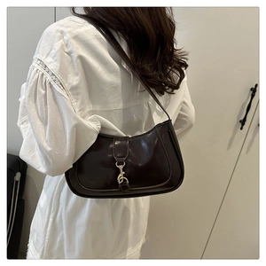 Detail of dark brown leather shoulder bag with a distinctive golden metal lobster clasp