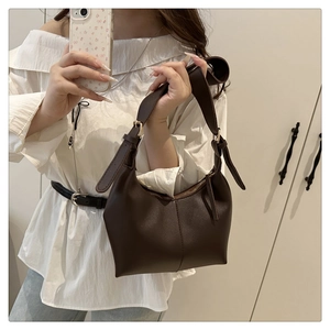 Detailed close-up of dark brown crescent shoulder bag with central stitching and wide strap