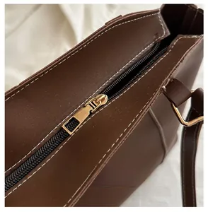 Detail of deep brown leather tote bag with gold zipper and white contrast stitching