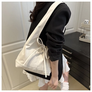 Seitenansicht der weißen Schultertasche mit Schleife, getragen von Model
