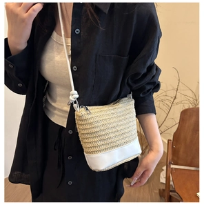 Detail of summer straw bucket bag with white leather base and thin shoulder strap