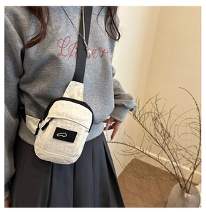 Detail of white nylon crossbody bag with black logo patch and metallic chain strap