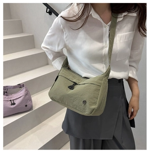 Dettaglio ravvicinato della borsa a tracolla in nylon verde macaron con tasca e logo in metallo