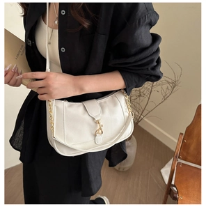 Detail of white baguette bag with gold chain strap and elegant ruched pleats