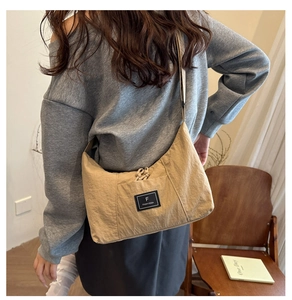 Detail of khaki canvas crossbody bag with brand logo label and adjustable shoulder strap