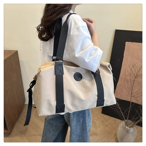 Detail view of large beige travel tote with black straps on a modern minimalist stand