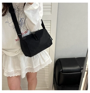 Detail of adjustable shoulder strap and double zipper on black nylon crossbody bag