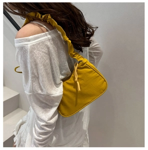 Detail of ginger yellow nylon shoulder bag featuring ruffled strap and knotted zipper pull