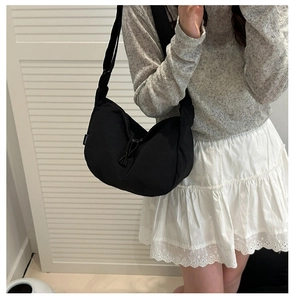Detail of black nylon crescent crossbody bag with adjustable wide strap on female model