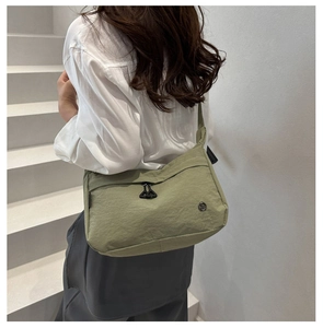 Dettaglio della borsa a tracolla in nylon verde che mostra il tessuto e la forma a mezzaluna