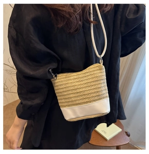 Detailed shot of straw crossbody bag with white leather base and zipper closure