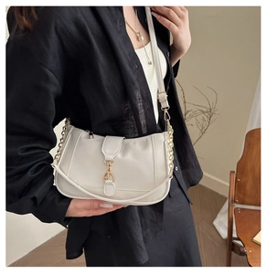 Close-up of a white crescent shoulder bag with golden chain and adjustable strap