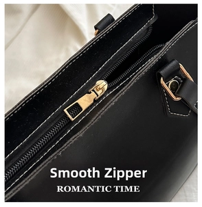Detail of smooth vintage gold zipper on black leather tote bag with white contrast stitching