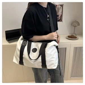 Detail of white large capacity travel bag with black handles and shoulder strap for gym