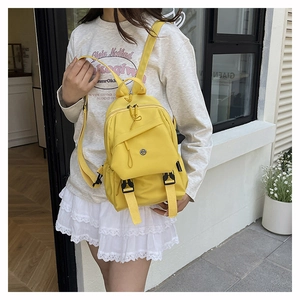 Bright yellow waterproof mini backpack worn by model with adjustable nylon straps
