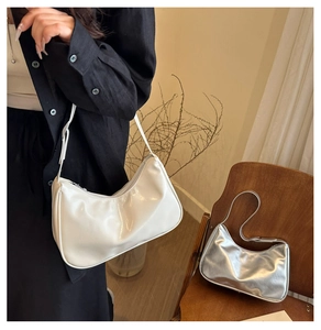 Close-up of minimalist hobo bags in white and silver finish on a wooden chair