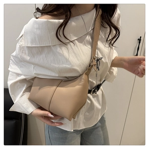 Detail of adjustable leather strap and vertical stitching on minimalist beige shoulder bag
