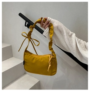 Detail of ginger yellow nylon shoulder bag with pleated strap and side bow design