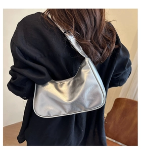 Model wearing a silver metallic Hobo underarm bag with a shiny cracked leather texture