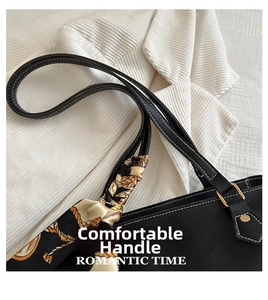 Detail of black leather tote bag featuring white stitching and printed silk scarf on handle