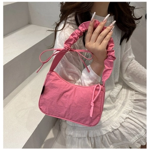 Detailed shot of pink nylon shoulder bag with ruffled handle and decorative bow accents