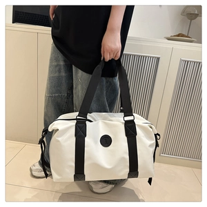 Detail of the black leather Fashion logo patch on a white oxford fabric travel bag
