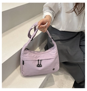 Détail d'un sac bandoulière en nylon lilas avec poche zippée et sangle réglable