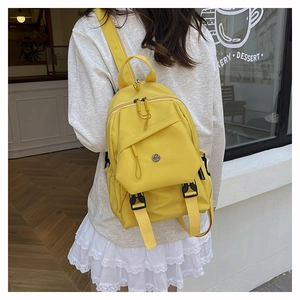 Close-up of bright yellow waterproof nylon backpack with fashion label and metal buckle