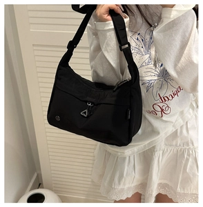 Détail du sac à bandoulière en nylon noir imperméable avec fermeture éclair et badge logo