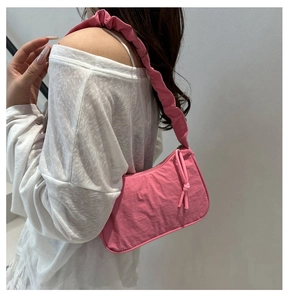 Detail of pink crescent bag showing ruffled shoulder strap and nylon fabric texture