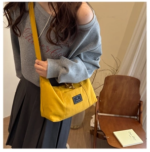 Close-up of ginger yellow canvas crossbody tote bag worn by a model in a lifestyle setting