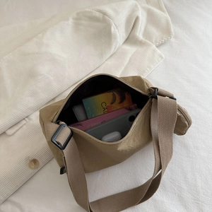 Khaki nylon crossbody bag with wide strap showing interior capacity for daily items