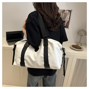 Rear view of a white large capacity travel bag with black straps in a cozy home setting