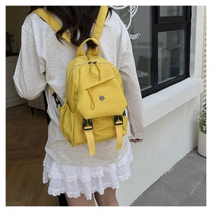 Detail view of bright yellow lightweight nylon backpack with multi-pocket design on model