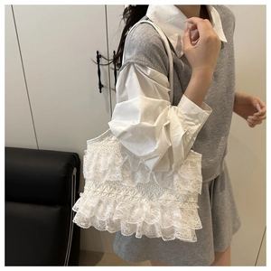 Close-up of layered white lace ruffles and floral texture on large beach tote bag