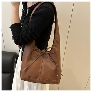 Elegante braune Tragetasche aus Ölwachsleder mit dekorativer Schleife auf der Vorderseite.