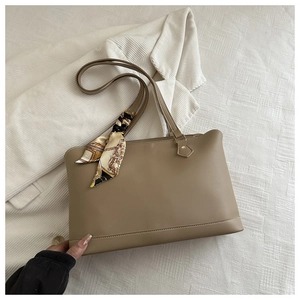 Close-up of khaki tote bag handle decorated with a printed silk scarf and zipper detail