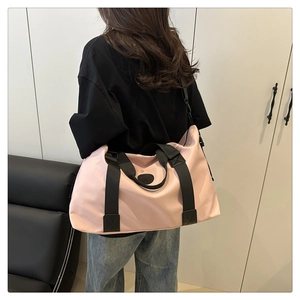 Pink large-capacity fitness bag with black straps worn by a model in a modern room