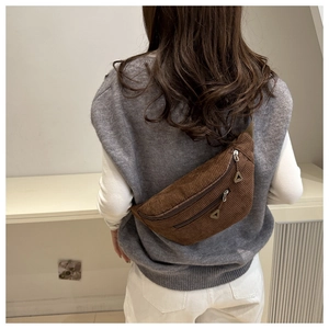Close-up of brown corduroy chest bag featuring dual zippers and metal triangle pendants