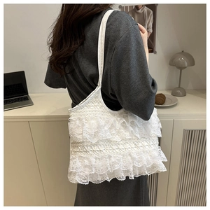 Detail of white lace ruffle tote bag with tiered lace layers on a model shoulder