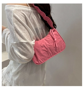 Pink nylon underarm bag with pleated wide strap and knot zipper detail on shoulder