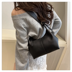 Detailed view of a black crescent shoulder bag in matte faux leather on model
