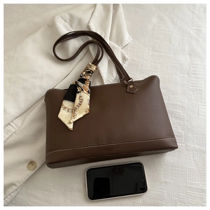 Detail of dark brown leather tote bag featuring elegant patterned silk scarf and contrast stitching