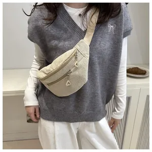 Detail of a beige corduroy crossbody bag with dual parallel zippers and textured fabric