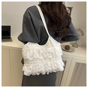 Detail view of white lace tote bag with tiered ruffles shown on model's shoulder