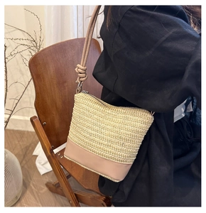 Detail of hand-woven beige straw shoulder bag with khaki faux leather base and zipper