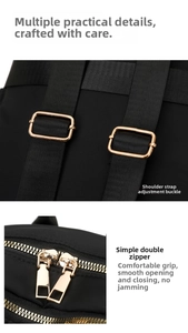 Detail of adjustable gold buckle and double metal zippers on black nylon backpack