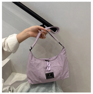 Detailed view of lilac nylon crescent bag with adjustable strap and brand logo