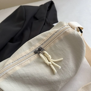 Lightweight beige nylon crossbody bag with water-resistant fabric and dual-zipper closure